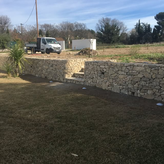 Aménagement paysager intégrant un mur en pierre et un escalier en pierre naturelle.